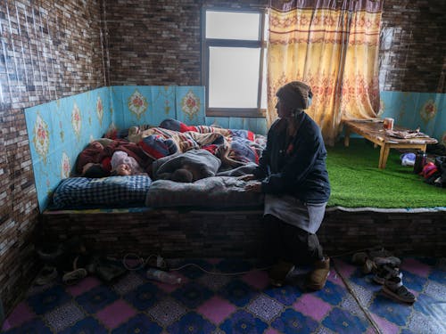 A woman sits on a bed in a room with a child