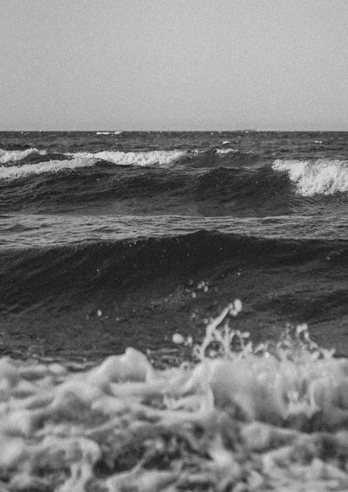 Black and white photo of waves crashing on the beach