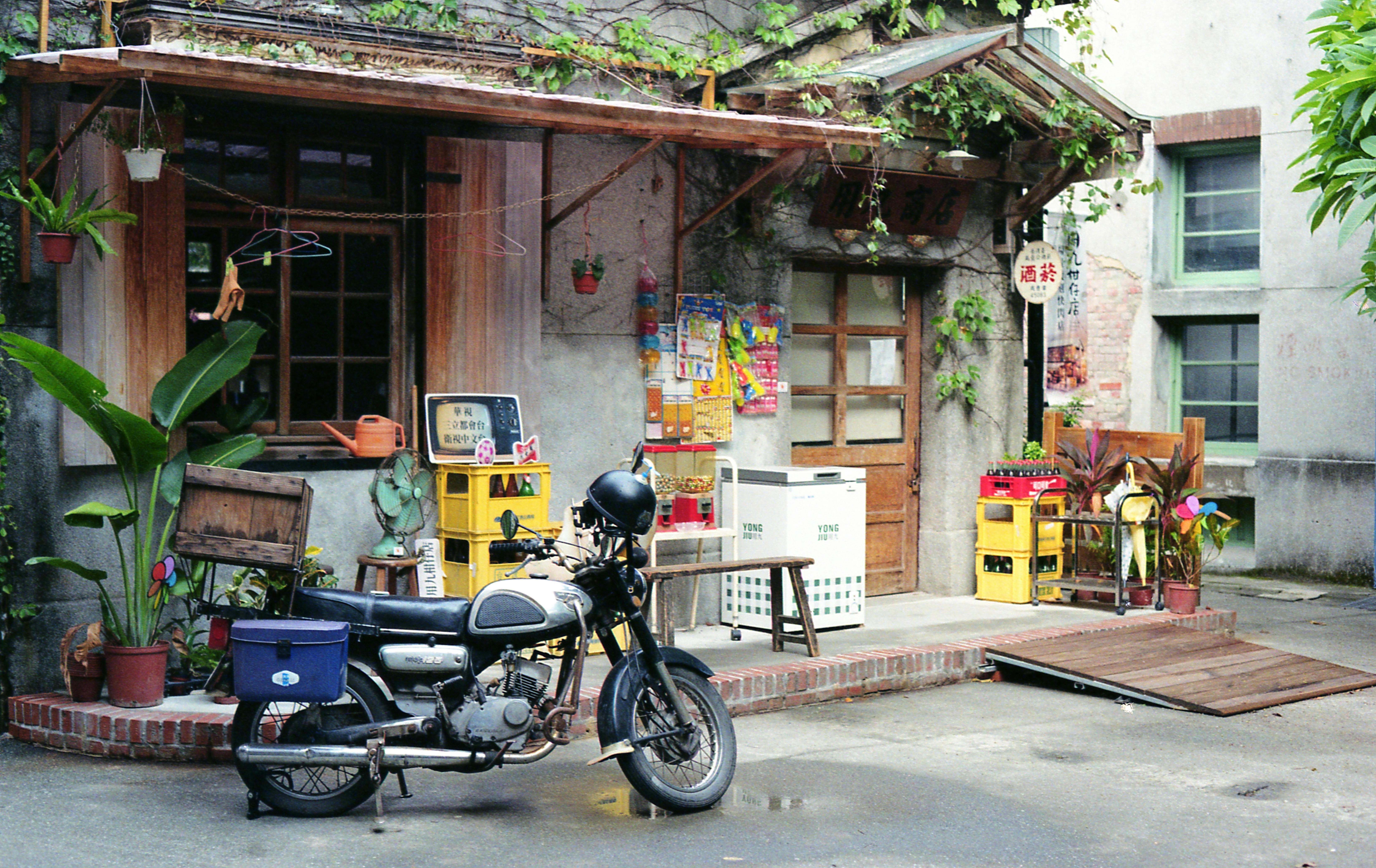 Vintage scooter parked in a rustic Taipei alleyway with plants and old architecture