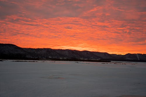 A sunset over a frozen lake with mountains in the background