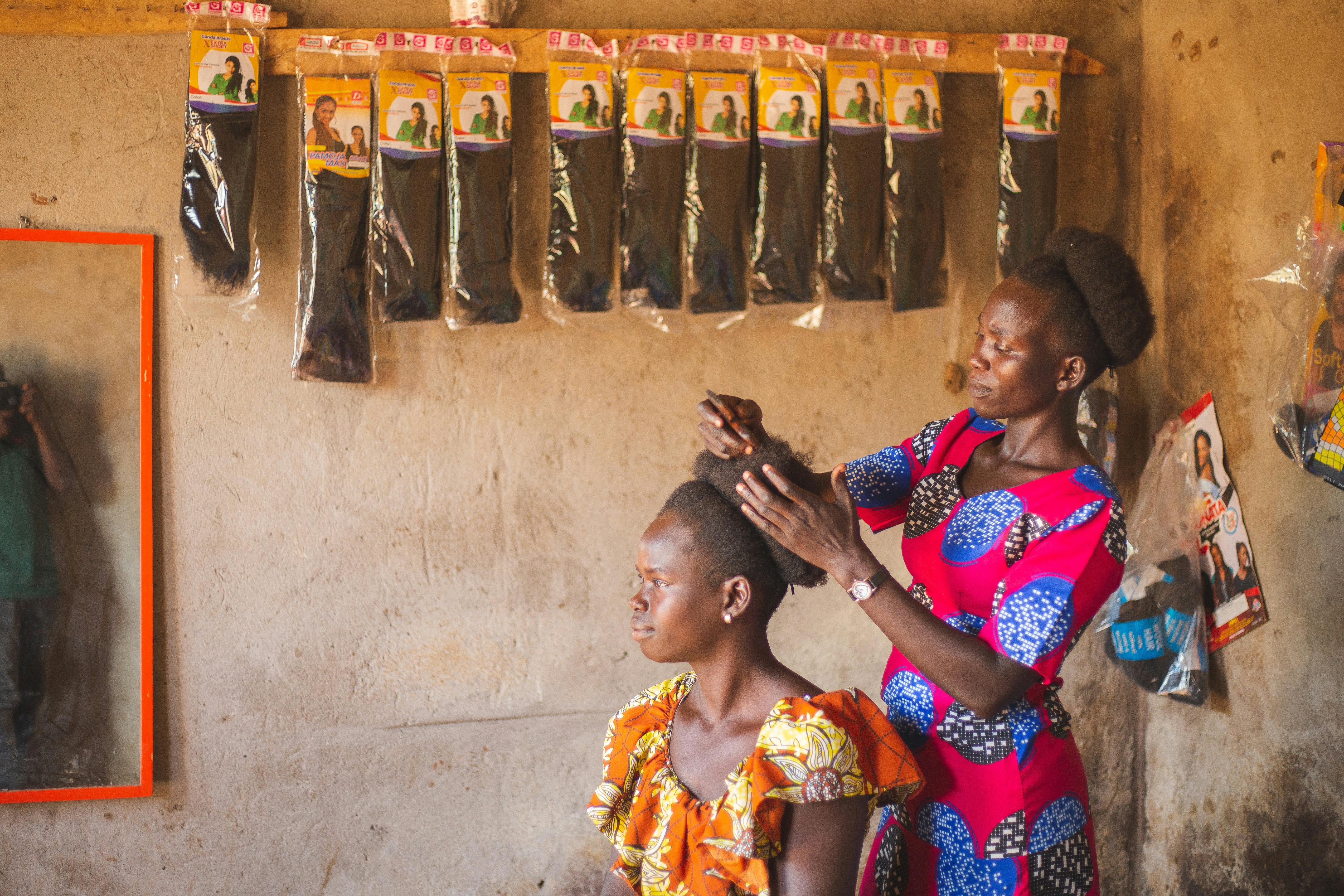 A hairstylist working on a customer's hair in a salon in Gulu, Uganda, showcasing African beauty and culture.