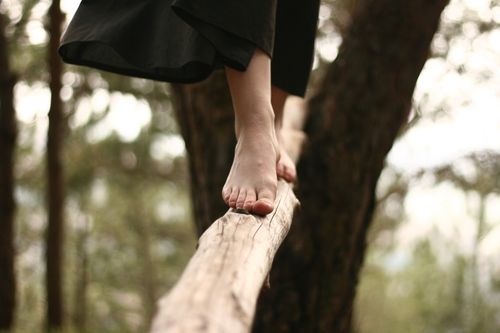 Free A woman walks barefoot on a log in a serene forest setting, capturing balance and focus. Stock Photo