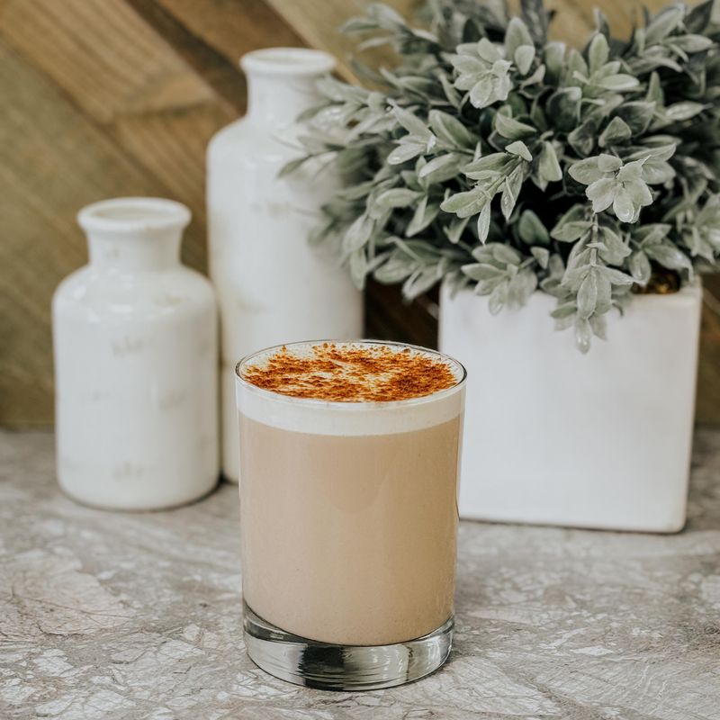 Creamy iced latte beside pale vases — photo by Jared Kaeb on Pexels