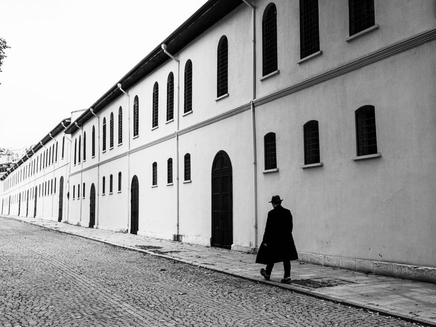 Black and white photo of a man walking by a historic building in Istanbul, Türkiye.