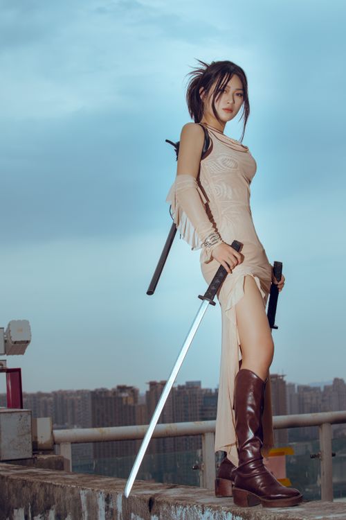 Free Asian woman in beige dress posing with swords on a rooftop with cityscape view. Stock Photo
