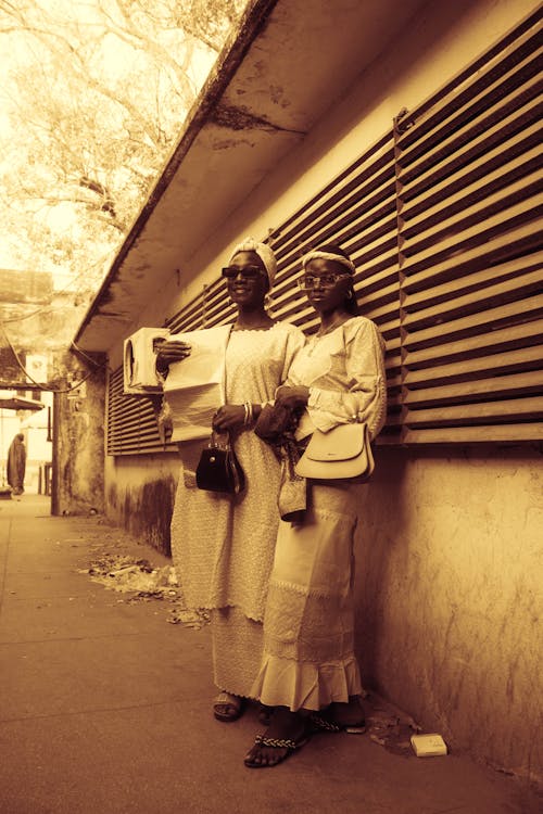 Two women standing next to each other on the side of a building