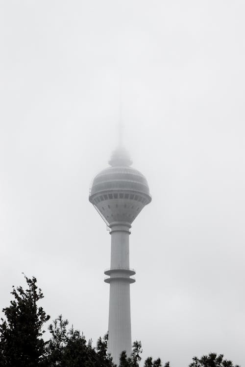 A black and white photo of a tower in the fog