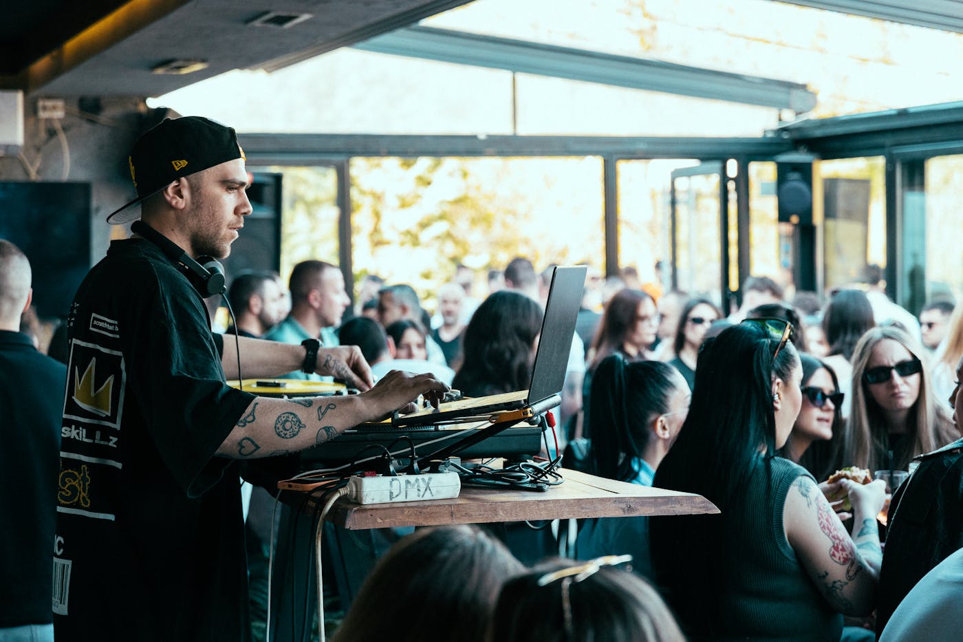 DJ al palco mentre persone ballano vicine nella pista affollata del locale