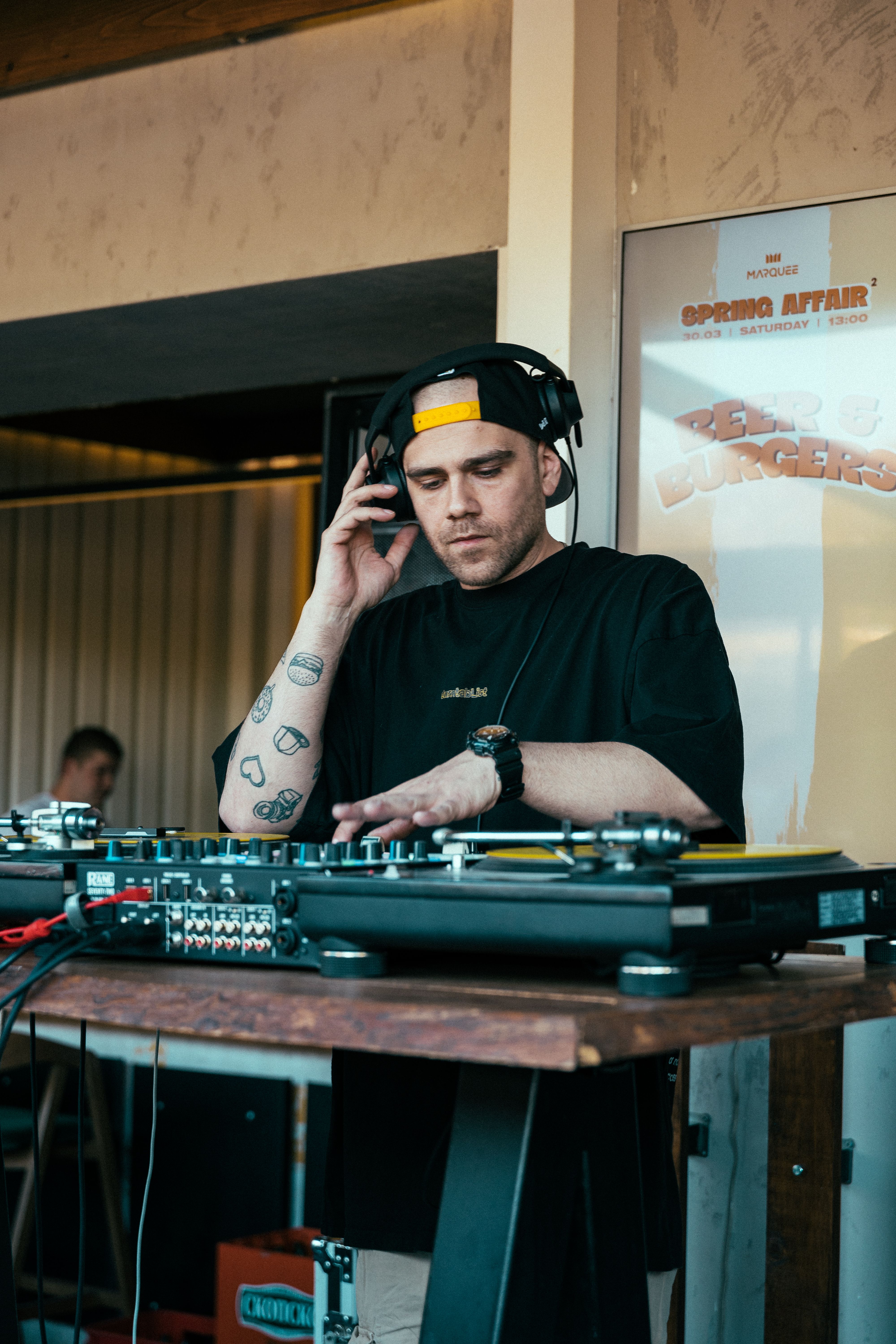 A DJ focused on mixing tracks at a vibrant outdoor party, creating an energetic atmosphere.