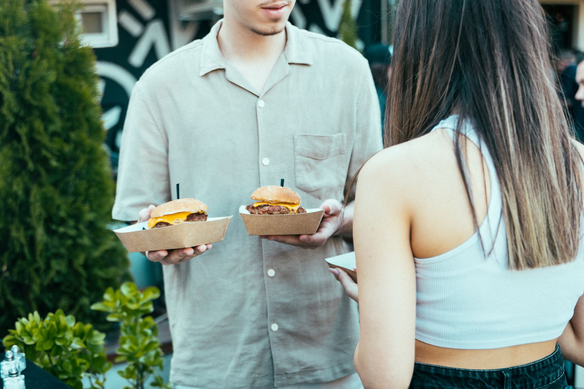 A casual outdoor scene with two people enjoying burgers, highlighting social dining and summer vibes.