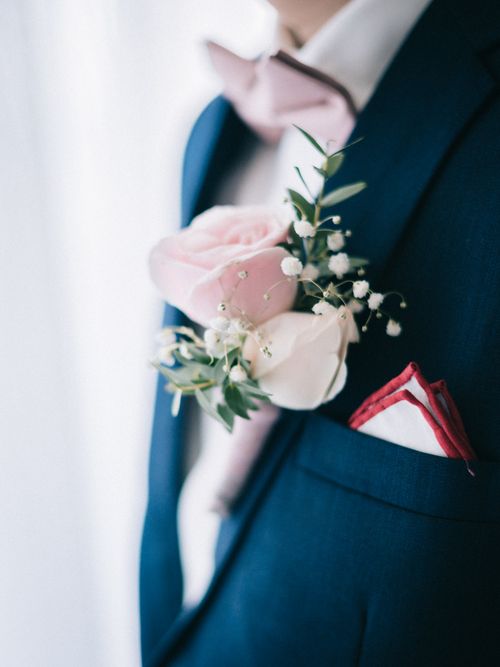 Free A groom adorns a navy suit with a pink and white rose boutonniere, exuding elegance. Stock Photo