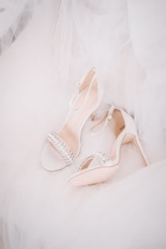 特写：优雅的白色结婚高跟鞋，鞋面装饰着珍珠，搭配飘逸的礼服