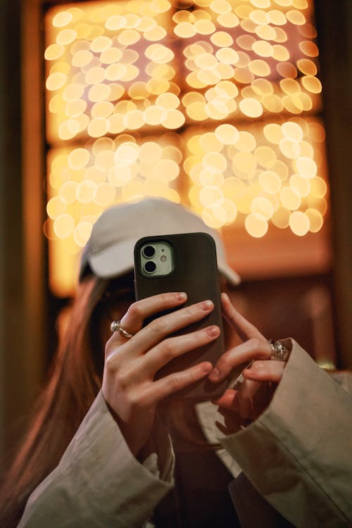 Girl capturing a photo on her phone against bokeh lights