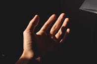 一只张开的手的特写，在灯光下投射出阴影，唤起神秘与情感