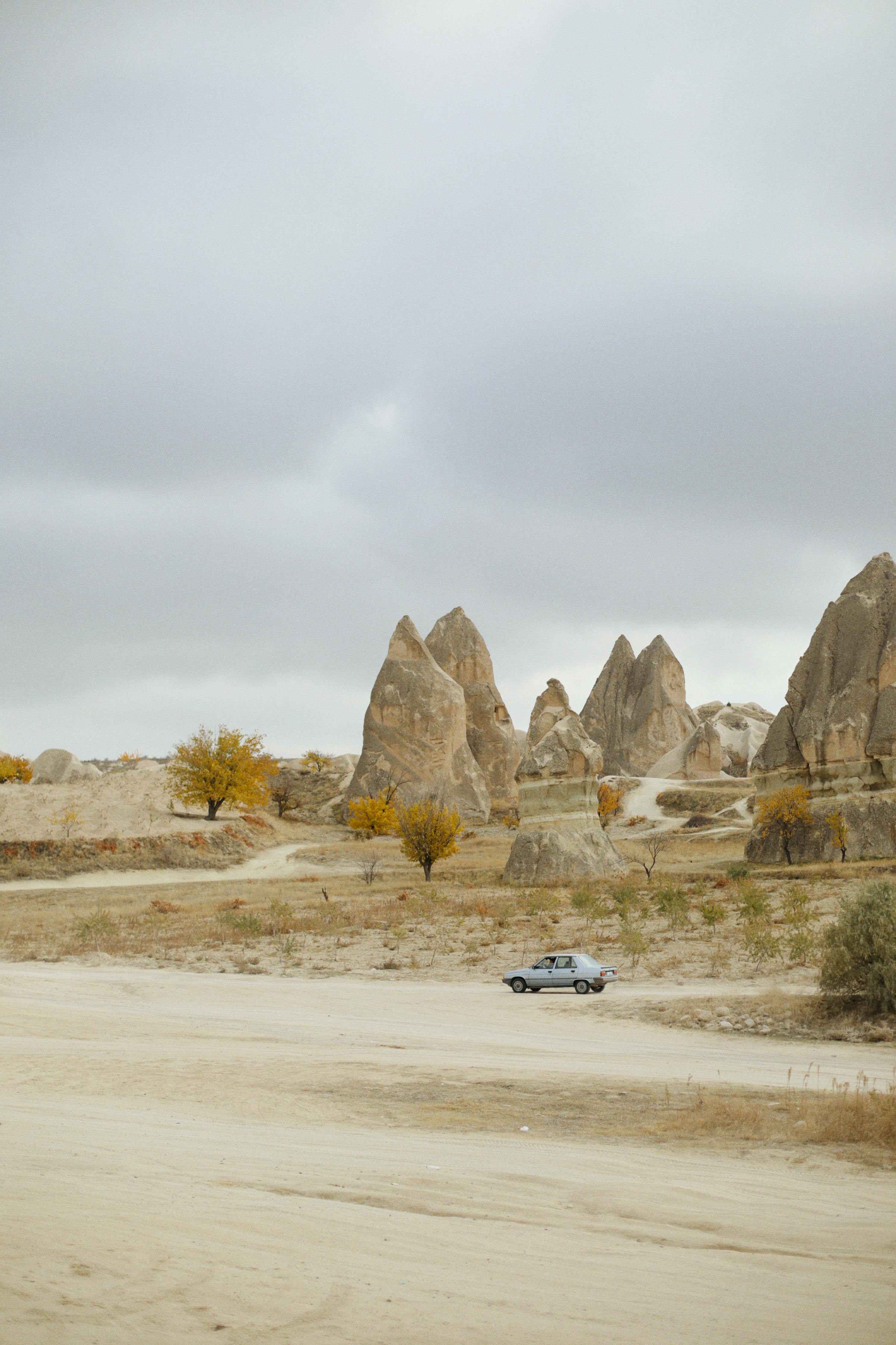 Captivating landscape of eroded rock formations in Cappadocia with a car on a rural dirt road.