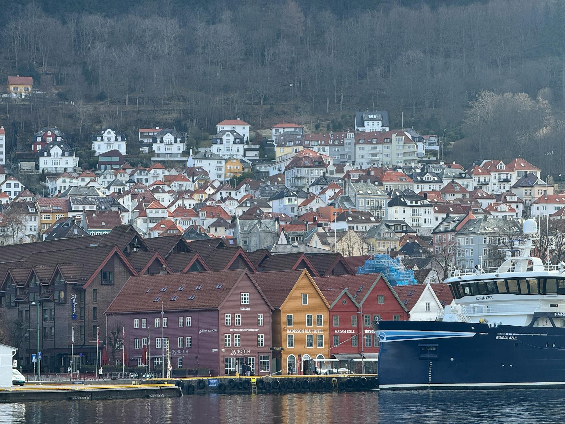Scenic view of Bryggen's colorful buildings and a ship docked at Bergen harbor.