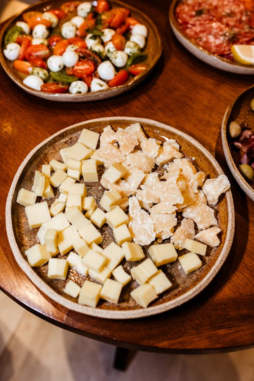 A table with plates of cheese, olives and other food