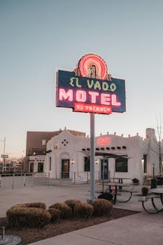 Neon-lit El Vado Motel sign against a clear evening sky, capturing retro charm.