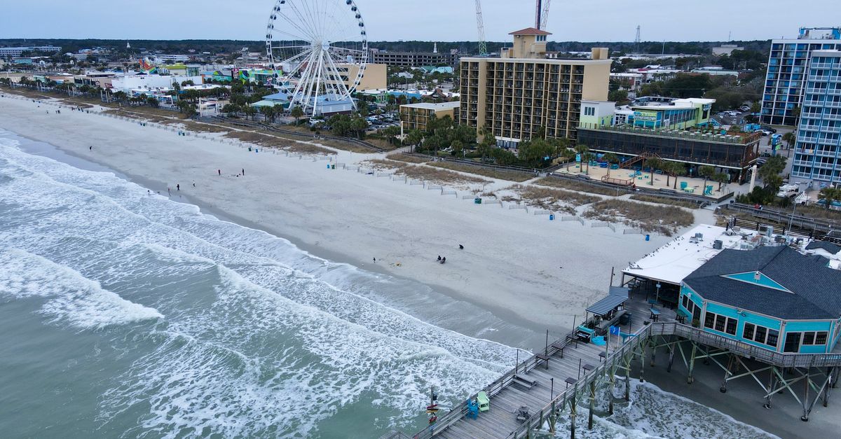 Aerial shot of Myrtle Beach with iconic pier and ferris wheel, capturing coastal beauty.