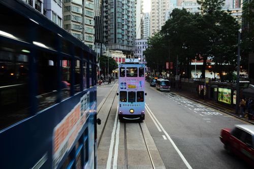 Free Hong Kong tram traveling through the bustling city streets with modern skyscrapers. Stock Photo