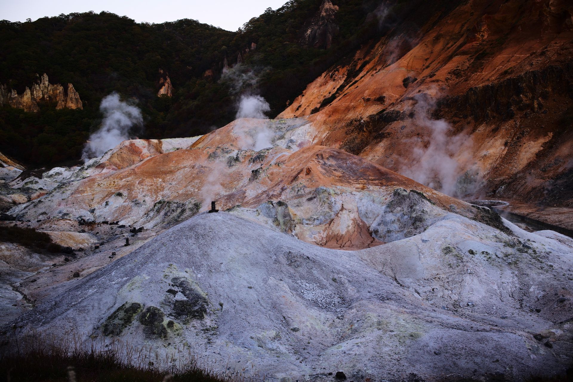 Dramatic geothermal terrain with steaming vents and colorful rock formations.