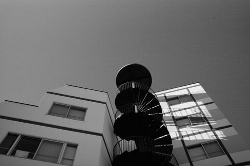 Free Low angle view of a spiral staircase against a clear urban skyline, monochrome style. Stock Photo