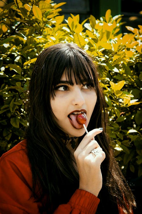 Free Woman in Brown Jacket Eating Lollipop Stock Photo