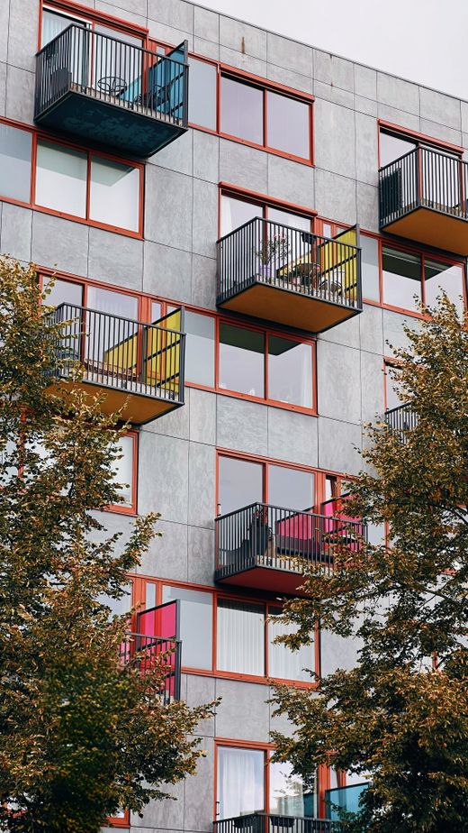 Residential block with colourful balconies above treetops — photo by Shehab Al-Qadhi on Pexels