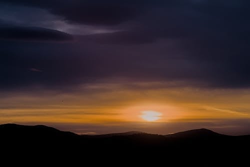 A sunset over the mountains with clouds