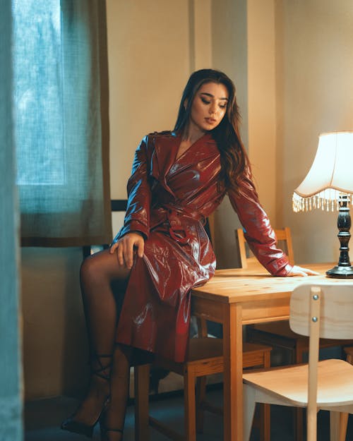 A woman in a red leather trench coat sitting at a table