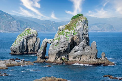 Two large rocks in the ocean with a body of water