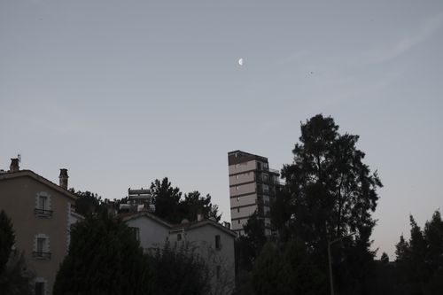 Free Serene cityscape in Bornova, İzmir with a visible half-moon against the evening sky. Stock Photo