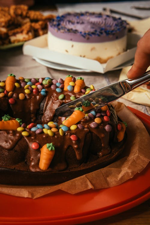 A person cutting into a chocolate cake with chocolate icing