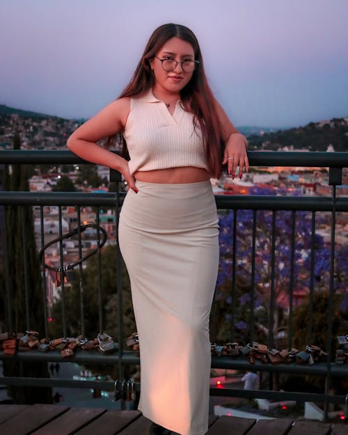 A woman in a white crop top and skirt