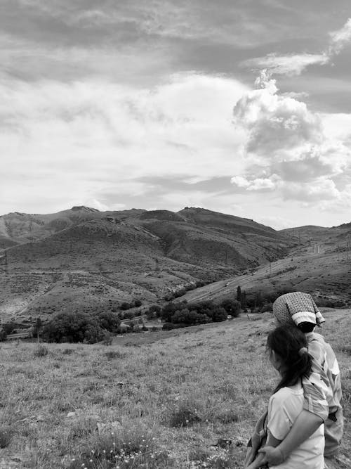 A black and white photo of two people standing in a field