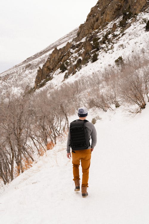 A man walking down a snowy trail with a backpack