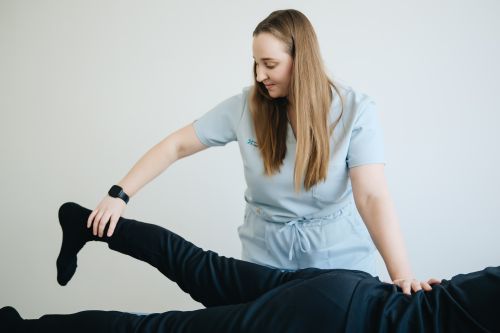 Free Female physiotherapist assisting patient in leg therapy session. Indoor clinical setting. Stock Photo