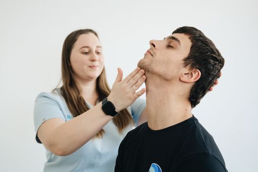 A physiotherapist performs therapy on a male patient's neck in Vilnius clinic.