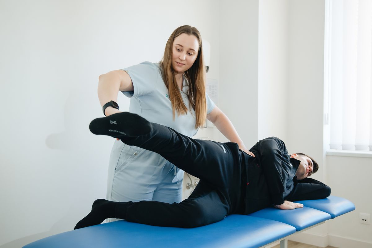 Physiotherapist assisting a patient with a leg therapy session in a clinic