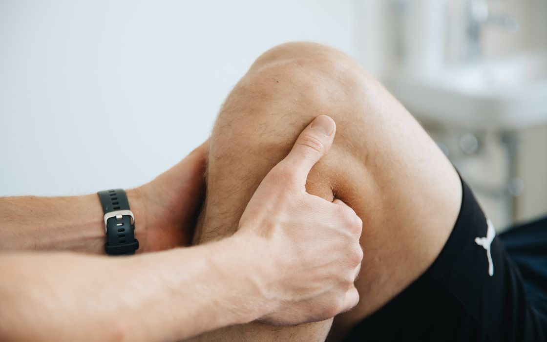 Close-up of a physiotherapist's hands working on a patient's knee during a therapy session