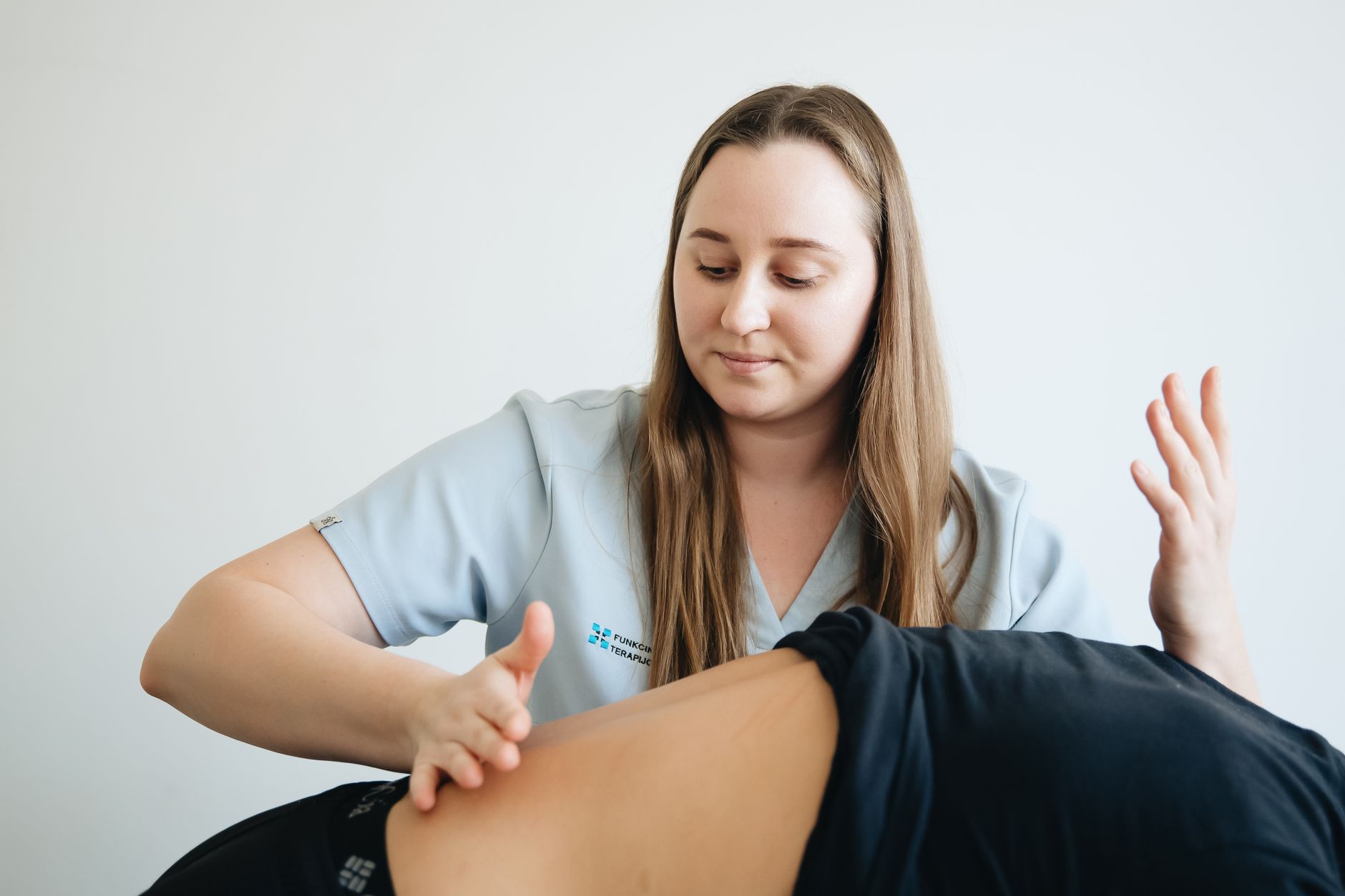 Female physiotherapist providing massage therapy to a patient in a clinic setting.