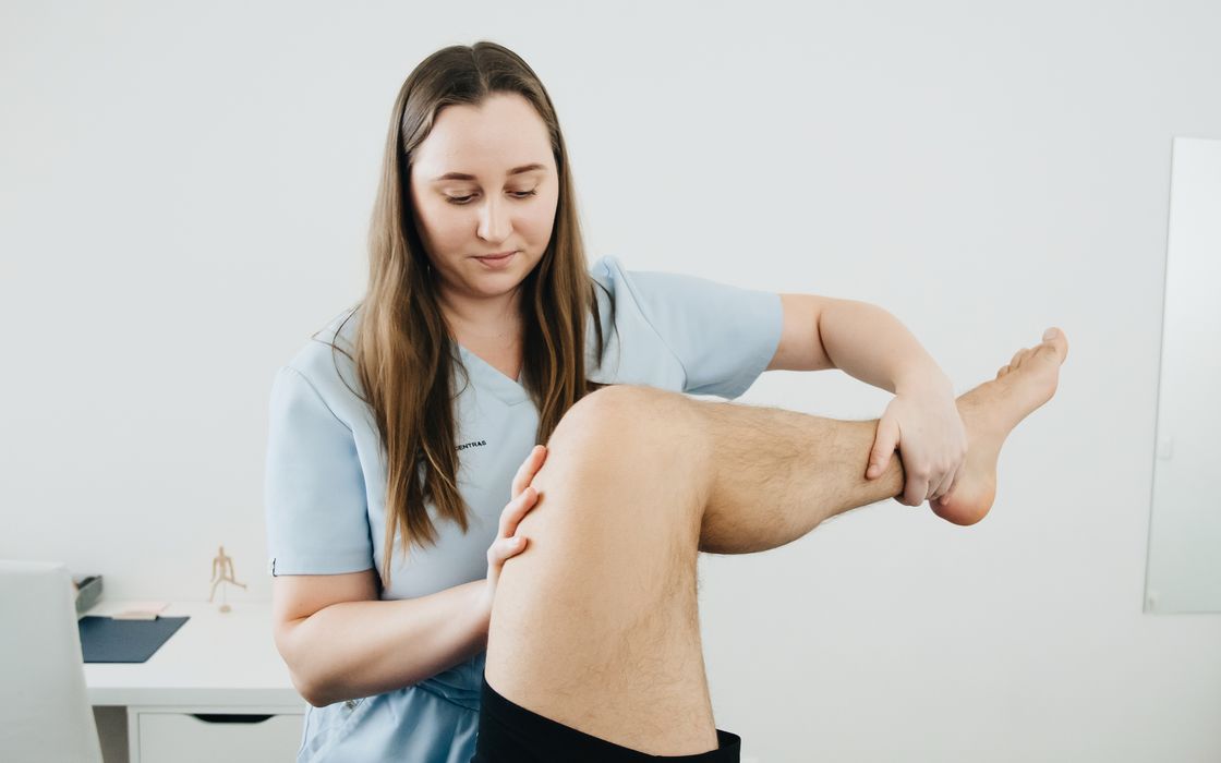 Physiotherapist gently bending a patient's knee during a rehabilitation session