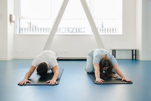 Two people doing yoga in an empty room