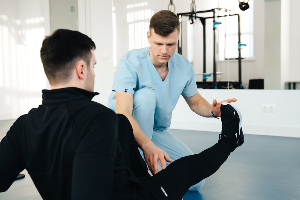 ALT: Kinésithérapeute examinant la jambe d’un patient, démonstration de prise en charge locale