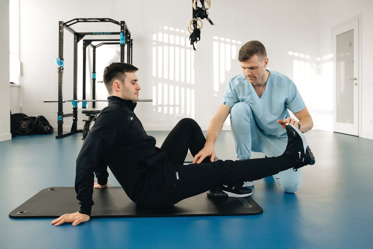 Physiotherapeut begleitet einen Patienten aktiv bei einer Rehabilitationsübung in einer modernen Praxis
