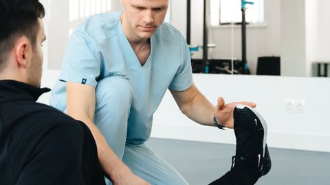 Experienced physiotherapist helps patient stretch leg in a modern clinic setting, focusing on rehabilitation.