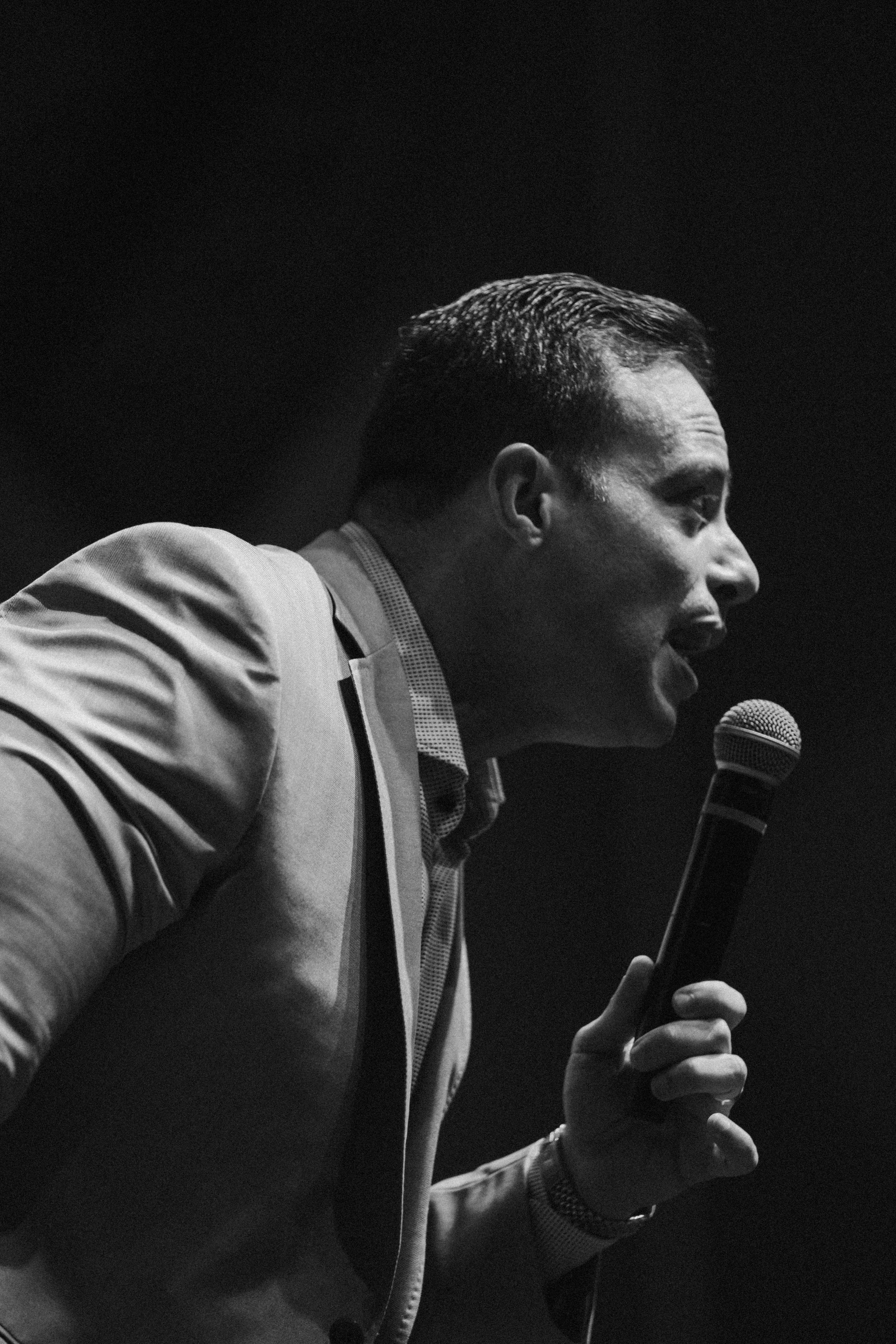 A powerful black and white portrait of a man speaking passionately into a microphone.