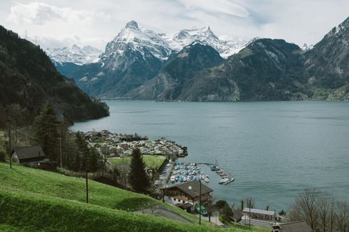 Free Picturesque village by the lake surrounded by majestic snow-capped mountains. Stock Photo