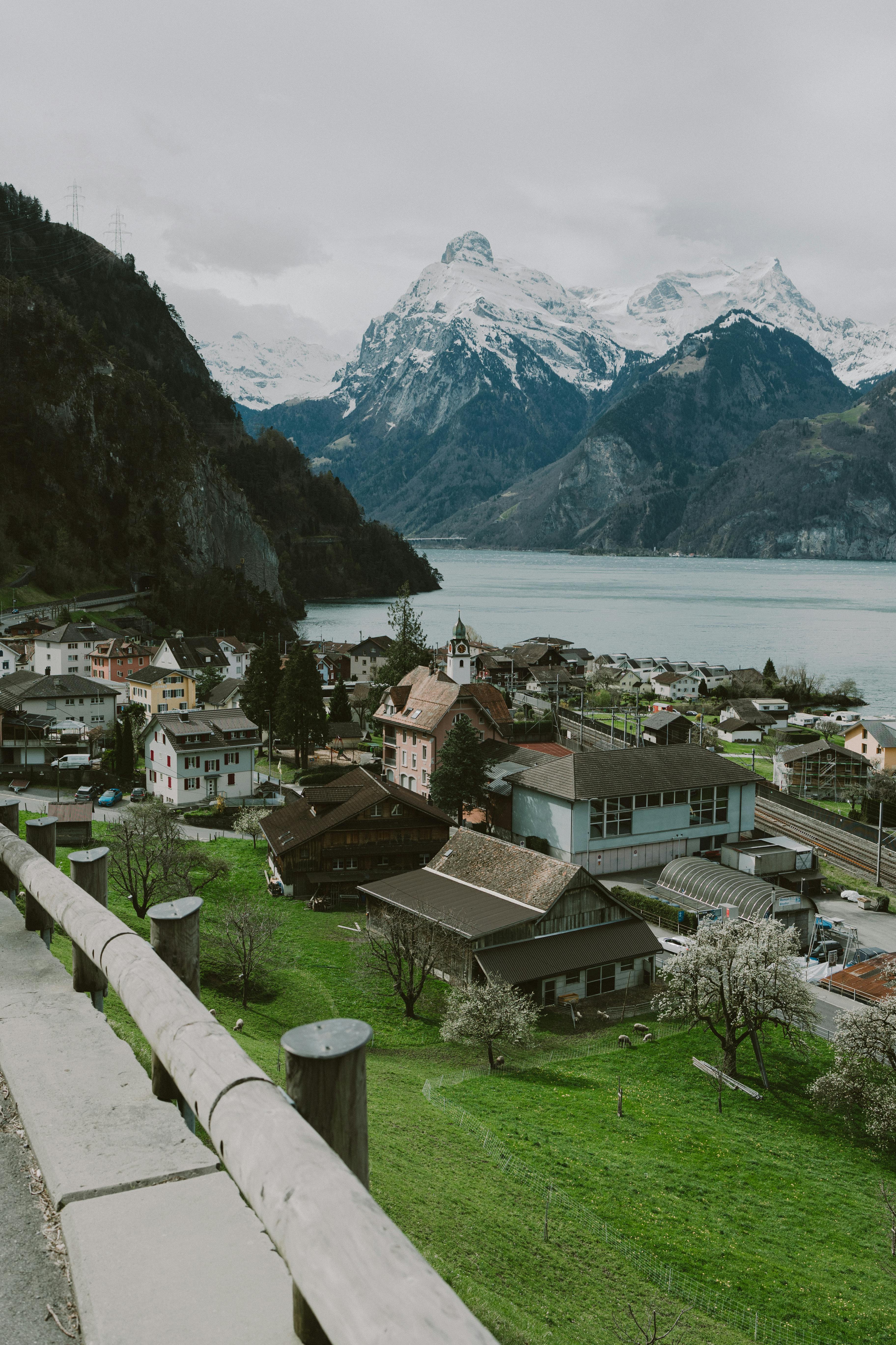 Picturesque village nestled by a serene lake against stunning snow-capped mountains.