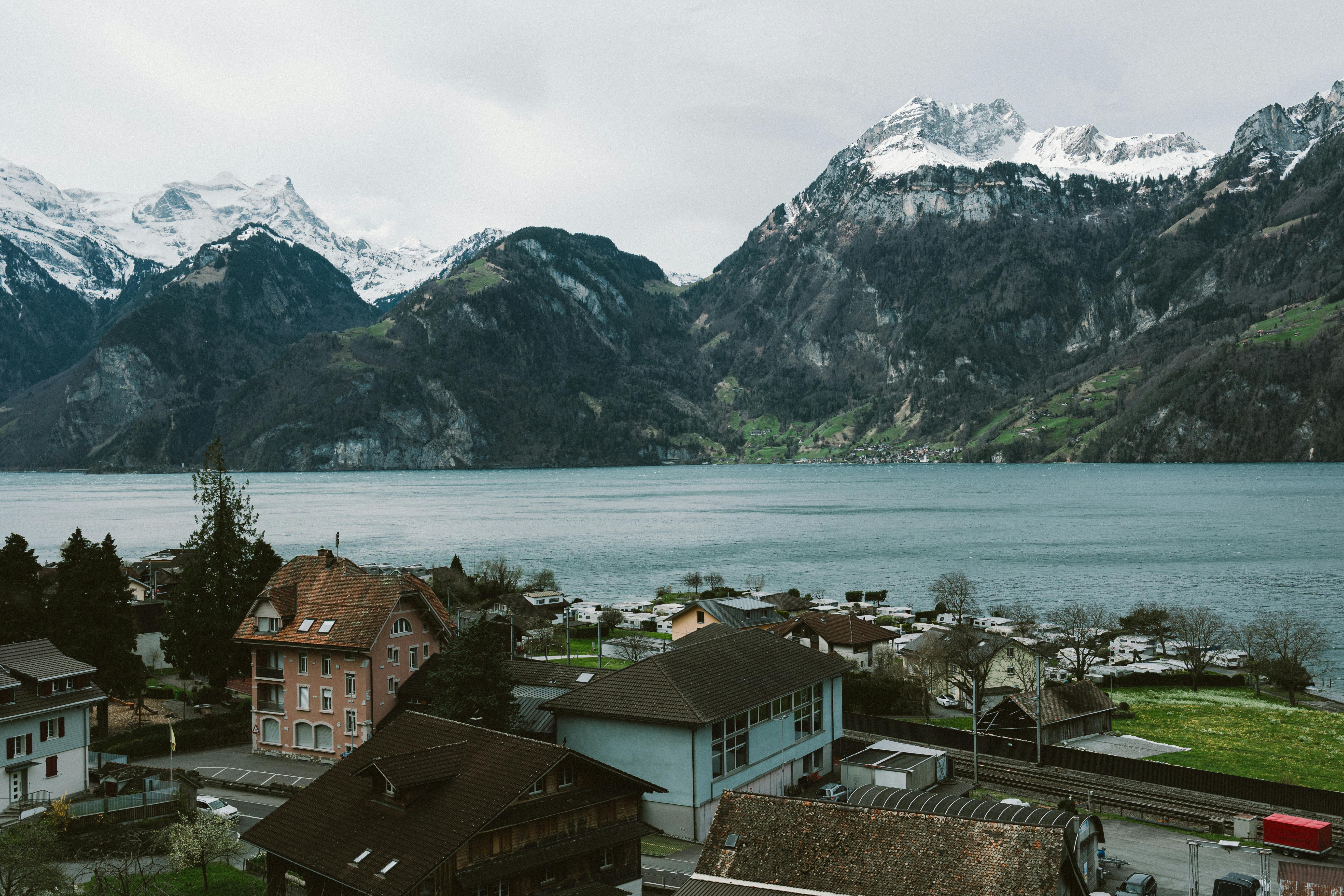 A stunning aerial view of a Swiss village by a lake, surrounded by snow-capped mountains.